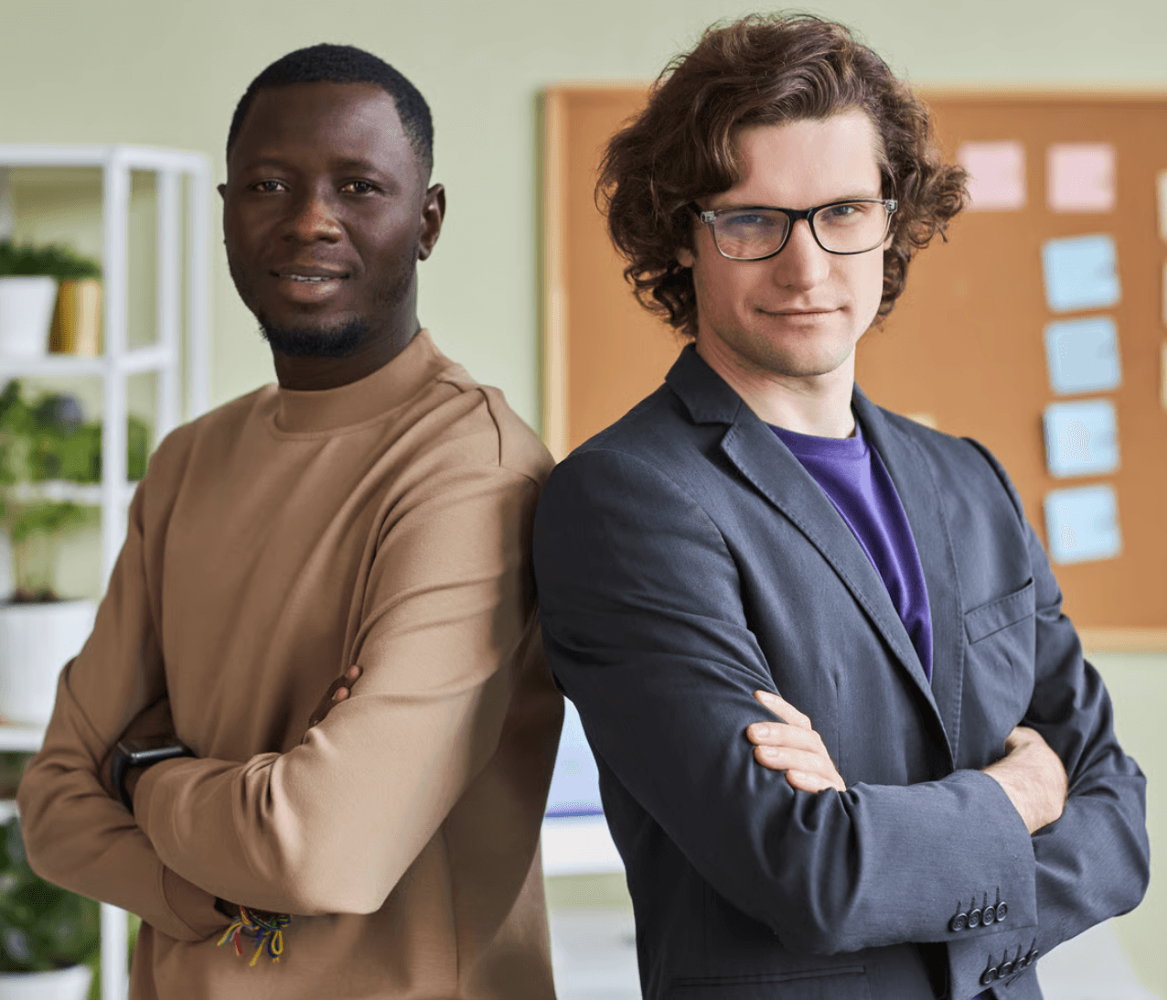 Two entrepreneurs standing back to back with arms crossed in an office