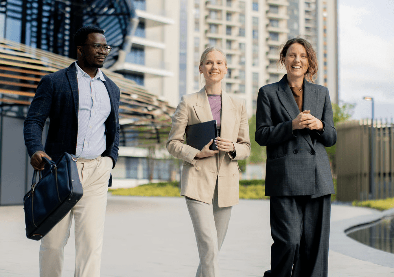 Three real-estate professionals in suits walking past a high-rise