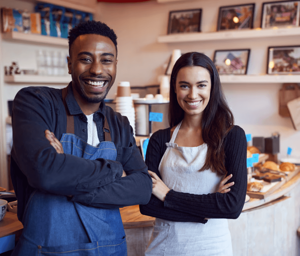 Two small-business owners smiling in their café