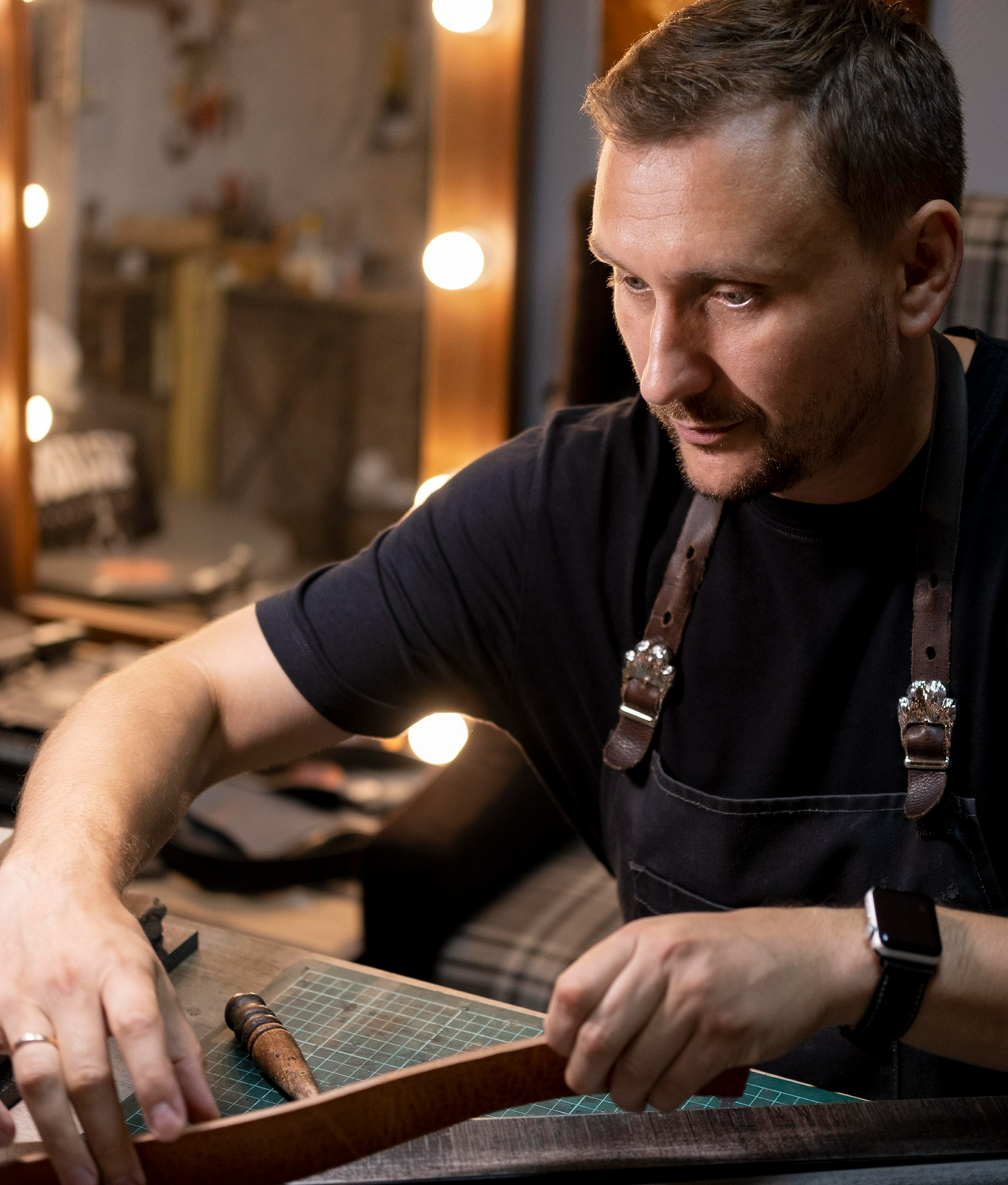 An artisan crafting a leather piece by hand in a warm workshop